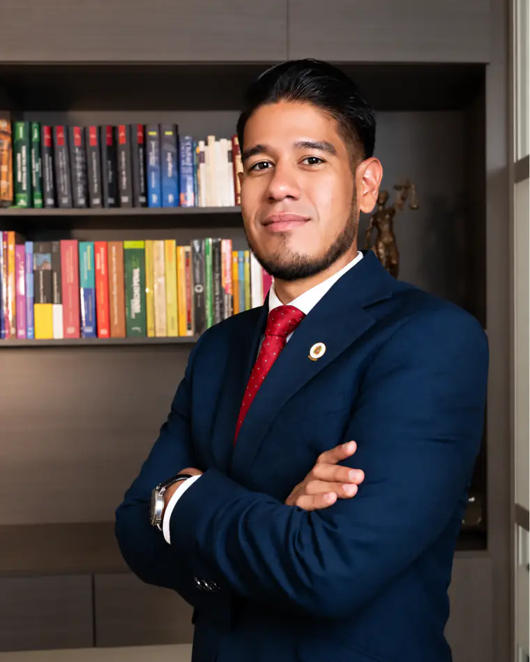 Retrato de Carlos Julián Ramírez Murillo en su oficina, de brazos cruzados frente a una biblioteca